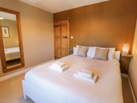A bedroom with a double bed two pillows folded towels a wooden door a wall mirror and a lamp on a wall shelf at Fron Goch Farm in Llanfair Talhaiarn