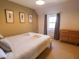 A bedroom with a bed with pillows and folded towels on it a window with curtains and a wooden dresser at Fron Goch Farm in Llanfair Talhaiarn