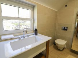A bathroom with a window above a sink and a wall-mounted toilet at Fron Goch Farm in Llanfair Talhaiarn