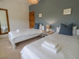 A bedroom with two single beds white bedding and blue pillows a wooden door a bedside table with lamp and a large mirror at Fron Goch Farm in Llanfair Talhaiarn