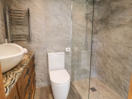 A bathroom with a toilet sink wooden cabinet and glass shower enclosure at Fron Goch Farm in Llanfair Talhaiarn