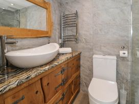 A bathroom with a toilet a sink on a wooden cabinet and a large mirror at Fron Goch Farm Llanfair Talhaiarn