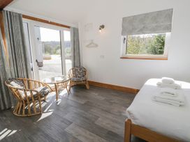 A bedroom with two wicker chairs and a small glass table near sliding doors and a bed with folded towels at Fron Goch Farm in Llanfair Talhaiarn