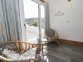A small seating area with two wicker chairs with floral cushions and a glass table near a sliding glass door at Fron Goch Farm in Llanfair Talhaiarn