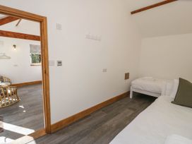 A bedroom with two single beds and a view into an adjacent room with rattan chairs at Fron Goch Farm in Llanfair Talhaiarn