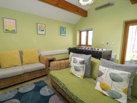 A room with wicker sofas with cushions a foosball table and framed pictures on the wall at Fron Goch Farm in Llanfair Talhaiarn