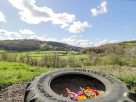 A large tire sandbox with children's toys and grassy hills in the background at Fron Goch Farm in Llanfair Talhaiarn