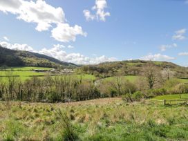 A rural landscape with grassy fields trees hills and scattered buildings at Fron Goch Farm in Llanfair Talhaiarn