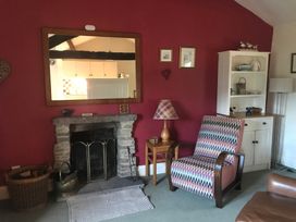 A living room with a fireplace and a bookshelf at Tyee Cottage Burton-In-Kendal