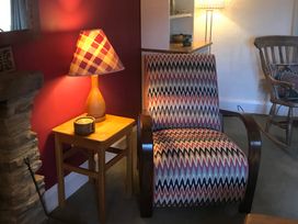 A living room with an armchair and a lamp at Tyee Cottage in Burton-In-Kendal