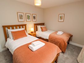 A bedroom with two beds, a lamp and artwork at Swallow's Nest Thornthwaite near Braithwaite