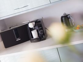 A kitchen with coffee maker, kettle, speaker, and bowl of fruit at Sandbanks in Praa Sands