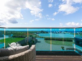 An outdoor balcony with a teapot and cup overlooking a parking area at Sandbanks in Praa Sands