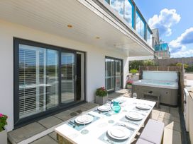 An outdoor patio with a hot tub and dining table at Sandbanks in Praa Sands