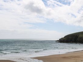 A beach with waves and a cliff at Sandbanks in Praa Sands