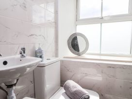 A bathroom with a toilet, sink, mirror, and towel at Tyddyn Elidir near Old Colwyn