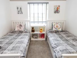 A bedroom with two beds and a shelf with toys at Tyddyn Elidir near Old Colwyn