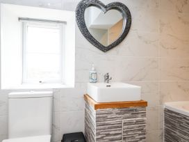 A bathroom with a sink, toilet, and mirror at Tyddyn Elidir near Old Colwyn