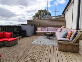 An outdoor seating area with a table and cushions at Tyddyn Elidir near Old Colwyn
