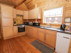 A wooden kitchen with cabinets a stove oven sink dishwasher and small appliances at Sun View Lodge in Llanbedr