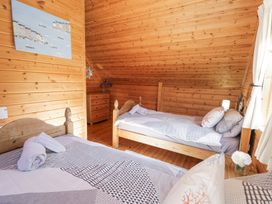 A bedroom with two single beds a wooden chest of drawers and a window with curtains at Sun View Lodge Llanbedr