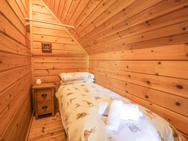 A small bedroom with wooden walls a single bed with animal print bedding a wooden nightstand and rolled towels at Sun View Lodge in Llanbedr