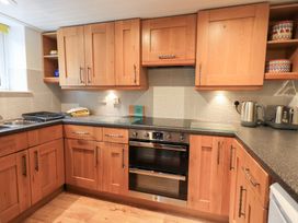 A kitchen with wooden cabinets and stainless steel appliances at Squirrel Cottage in Bassenthwaite