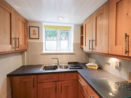 A kitchen with wooden cupboards and a sink at Squirrel Cottage in Bassenthwaite
