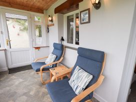 A conservatory with two armchairs and a table at Squirrel Cottage in Bassenthwaite