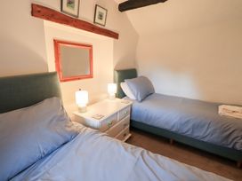 A bedroom with twin beds and a nightstand at Squirrel Cottage in Bassenthwaite