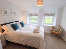 A bedroom with a bed and windows at Squirrel Cottage Bassenthwaite