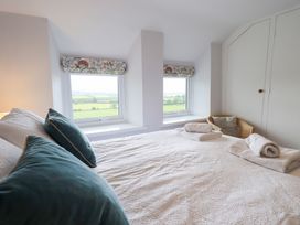 A bedroom with a bed and windows at Squirrel Cottage in Bassenthwaite