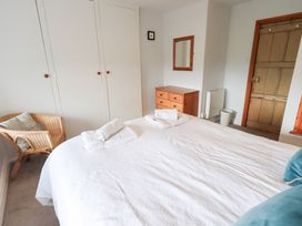 A bedroom with a bed and a chair at Squirrel Cottage in Bassenthwaite