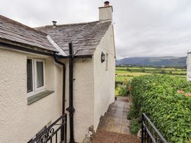 An exterior view of a house with a pathway and vegetation at Squirrel Cottage in Bassenthwaite