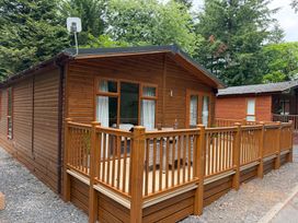 A wooden lodge with a deck and railing at Cherry Tree Lodge Calgarth 37, White Cross Bay near Windermere