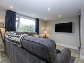 A living room with a sofa and a television at Caledfryn Tyn-y-Gongl