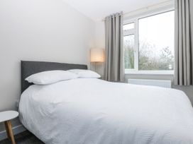 A bedroom with a bed, lamp, and window at Caledfryn, Tyn-y-Gongl