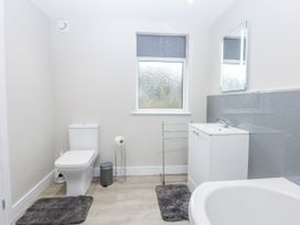A bathroom with a toilet, wash basin, and bath tub at Caledfryn in Tyn-y-Gongl