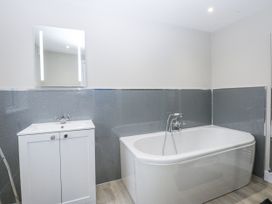 A bathroom with a bathtub and a vanity sink at Caledfryn Tyn-y-Gongl