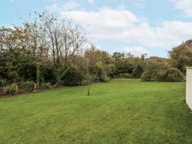 A garden with grass and trees at Caledfryn in Benllech