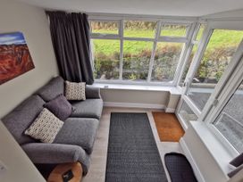 A snug with a sofa and large windows at Caledfryn in Benllech