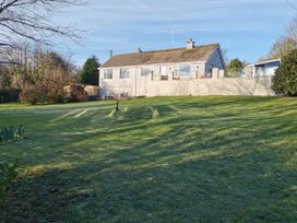 A house with a lawn and trees at Caledfryn in Benllech