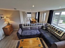 A living room with a sofa and dining area at Caledfryn in Benllech