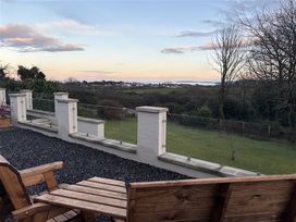 An outdoor area with wooden chairs and a view at Caledfryn in Benllech