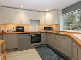 A kitchen featuring cabinets, a refrigerator, and appliances at Caledfryn in Benllech