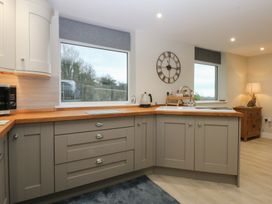 A kitchen with cabinets, a sink, and a window at Caledfryn in Benllech