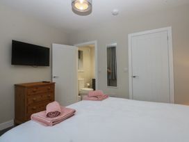 A bedroom with a double bed and a dresser at Caledfryn in Benllech
