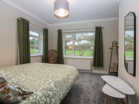 A bedroom with a bed and windows at Caledfryn Benllech