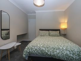 A bedroom with a bed and mirror at Caledfryn in Benllech