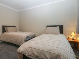 A bedroom with two beds and a lamp at Caledfryn in Benllech